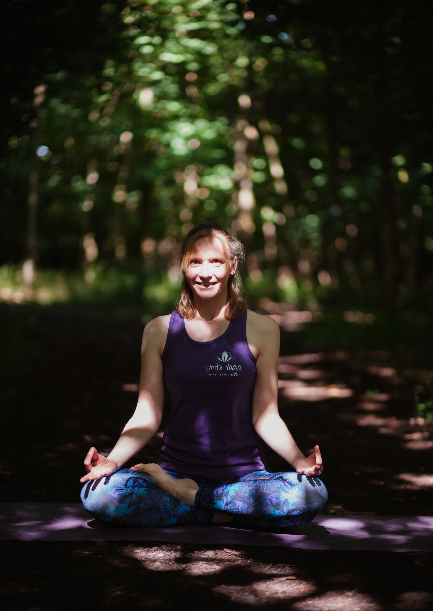 Sarah sitting in lotus pose in a woodland setting